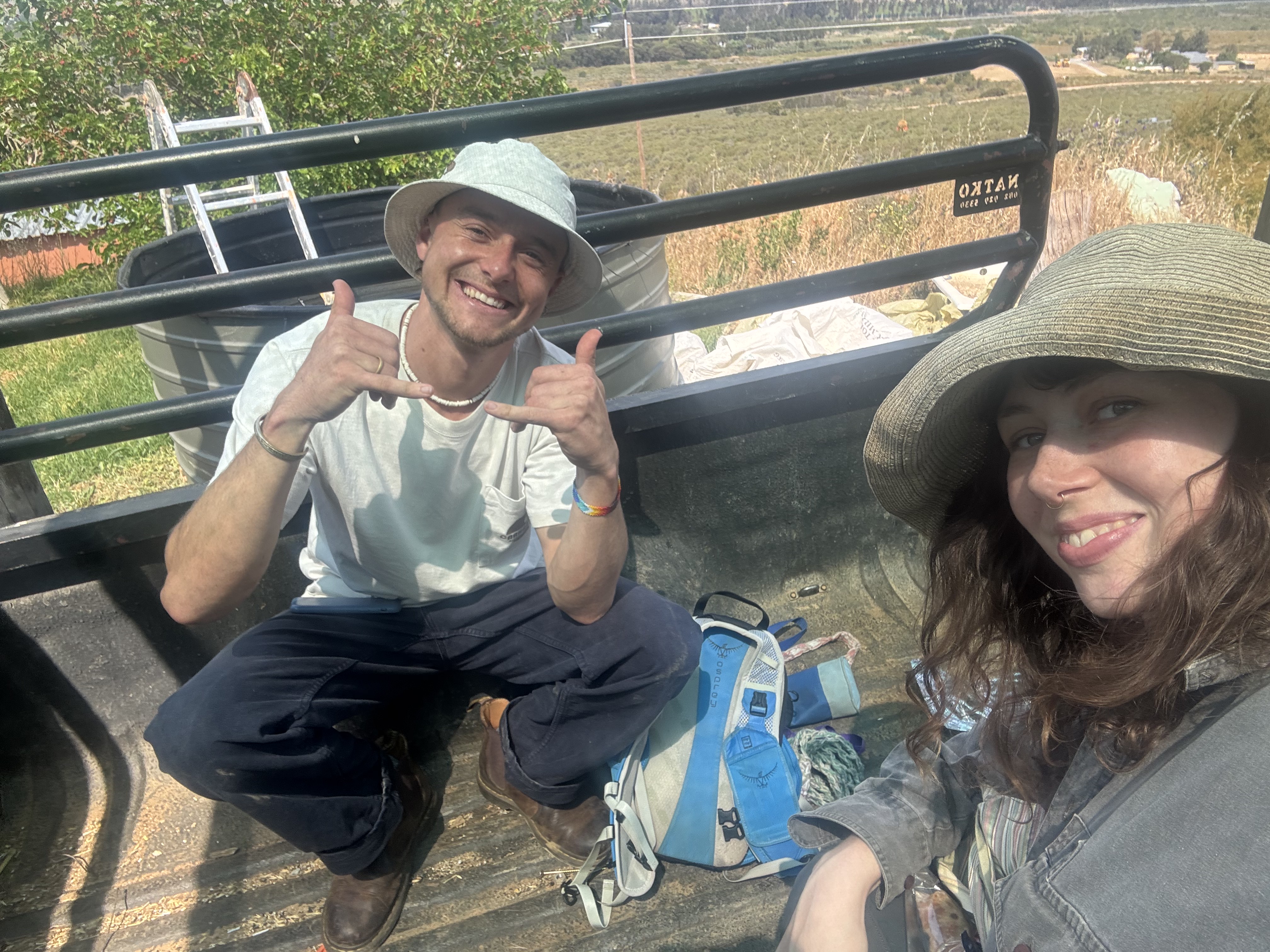 Genevieve and Milo sitting on the back of a bakkie in the sun