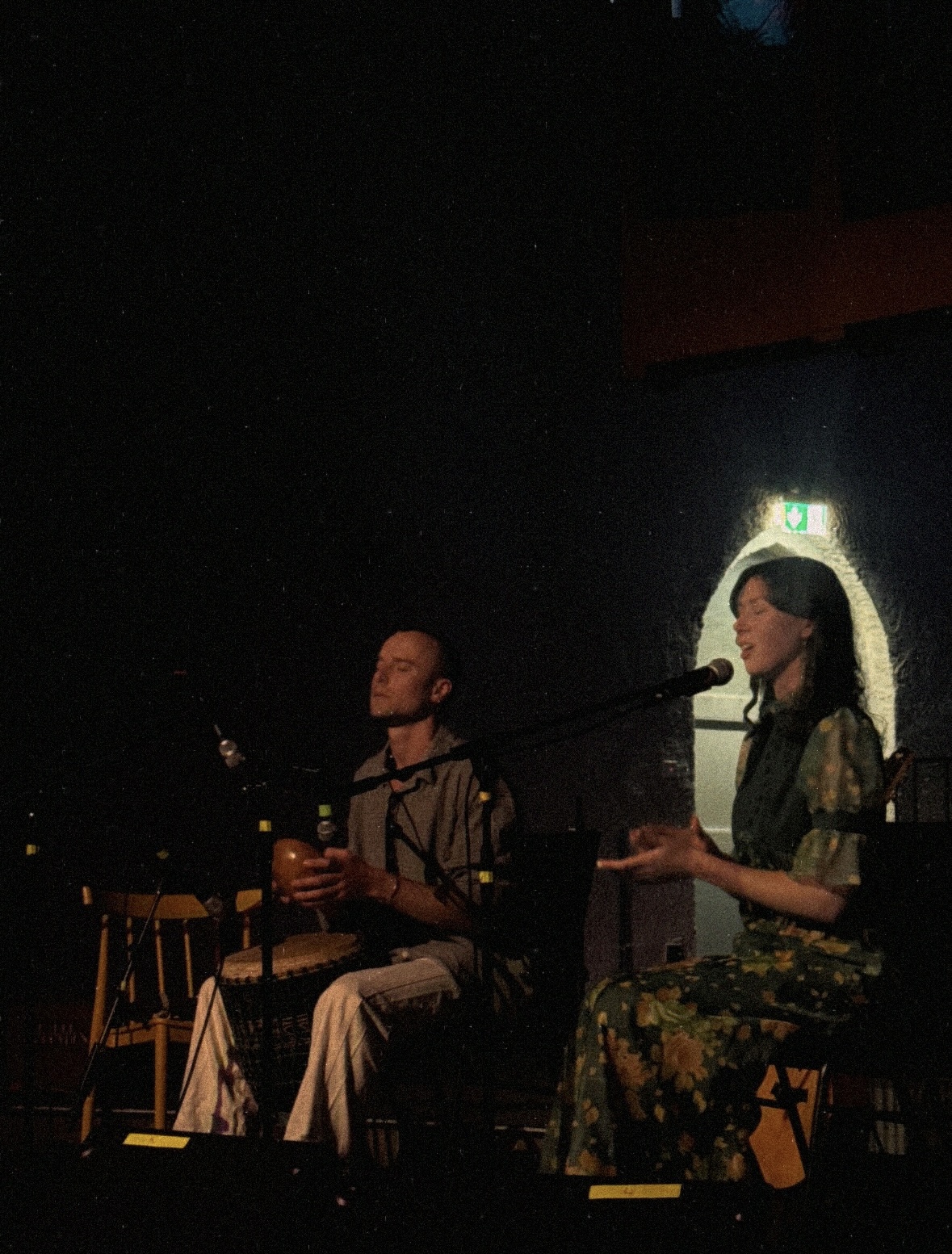 Genevieve singing while Milo plays djembe in a dark candlelit room